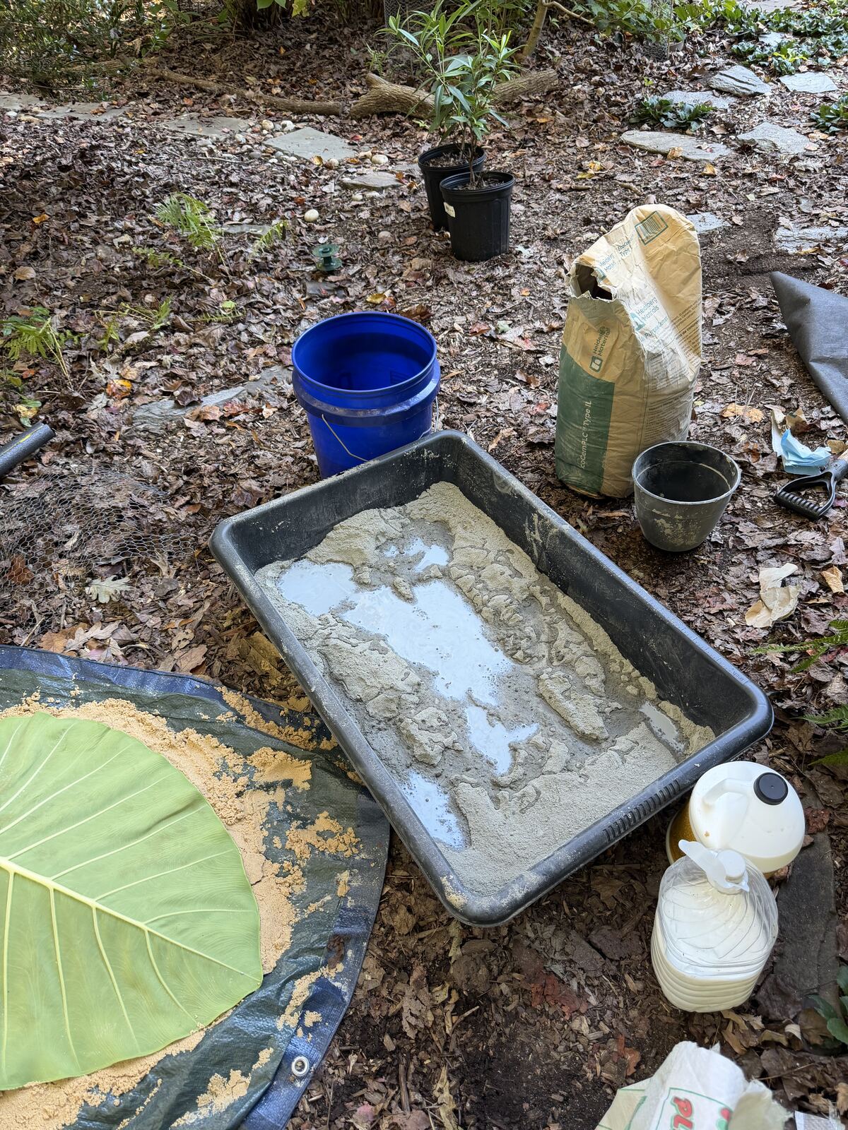 Mixing station with a tray of cement, a bag of patch cement, a bucket, and adhesive bottles