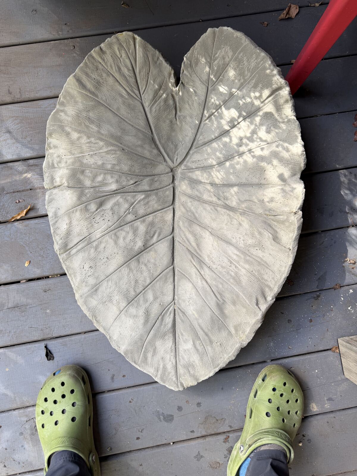 Finished gray leaf cast on a deck with green Crocs at the bottom for scale