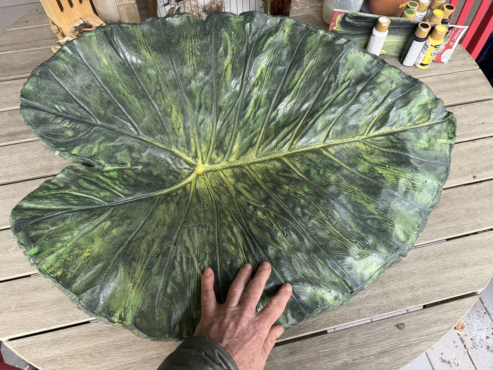 A hand across the finished, sealed leaf cast showing the glossy painted veins